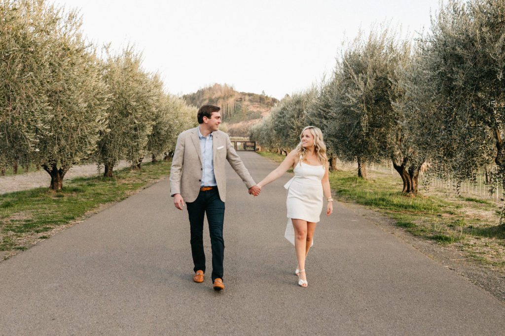 walking hand in hand at the napa valley reserve after engagement proposal.