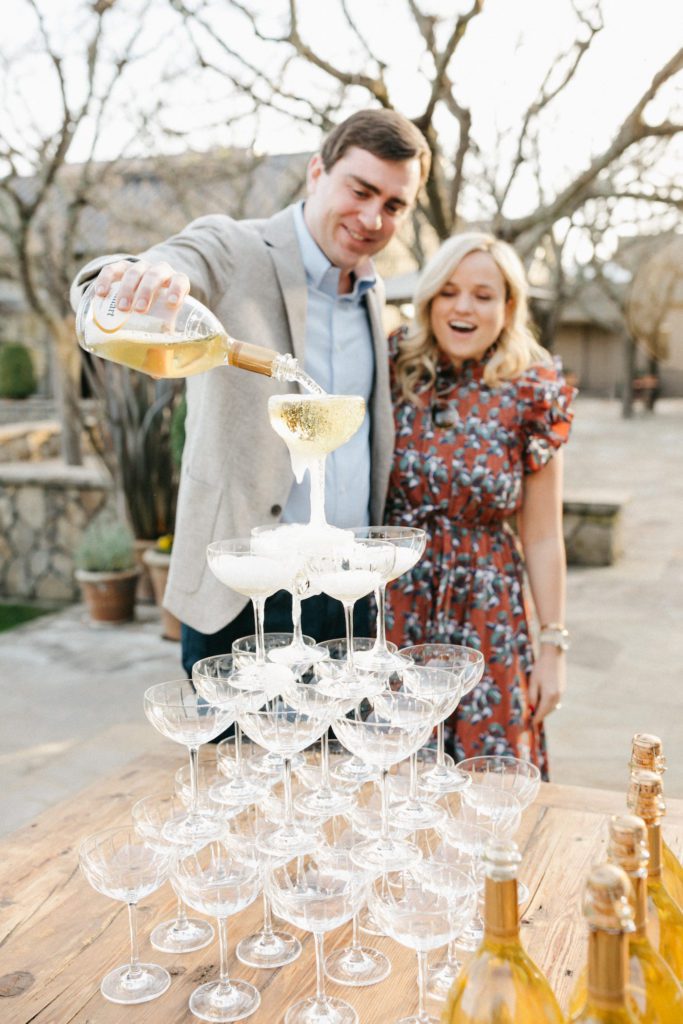 couple pours champagne for champagne tower at their surprise proposal and engagement party
