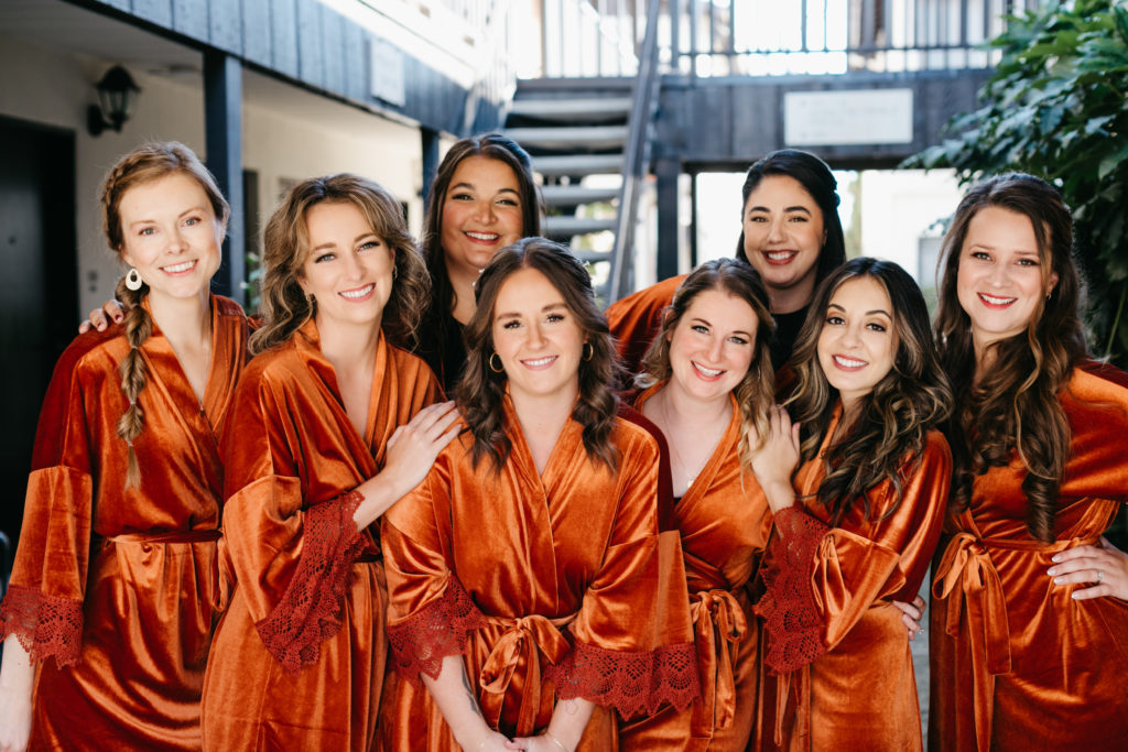 Bride and bridesmaids wearing terracotta or burnt orange robes for wedding day.
