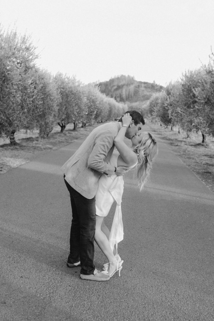 couple kisses on driveway of the napa valley reserve after surprise proposal