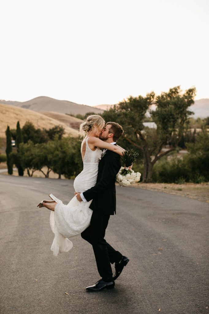 Bride jumping in her groom's arms at their summer wedding at Viansa, Sonoma.